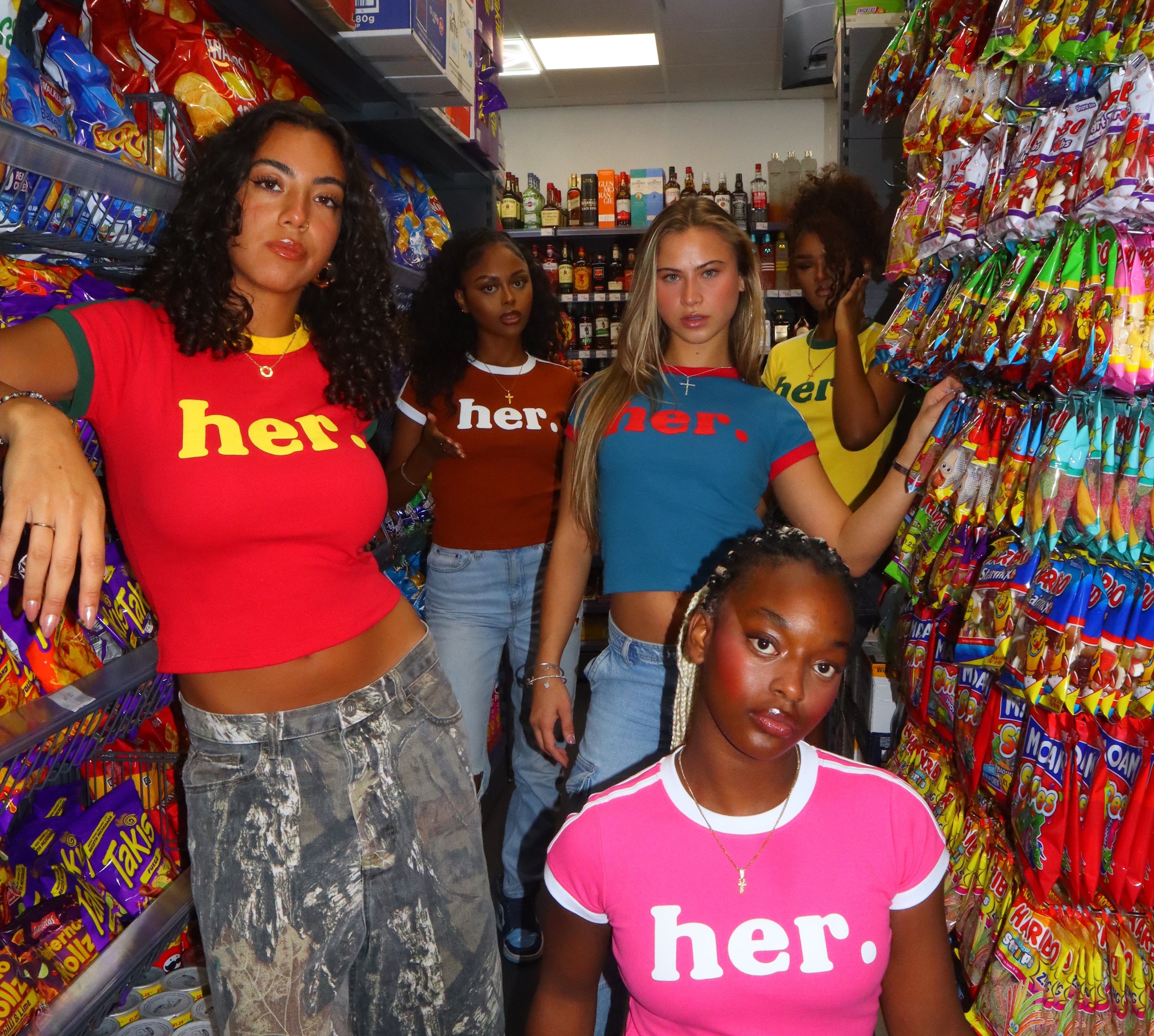 Three people wearing 'her' t-shirts in a candy store